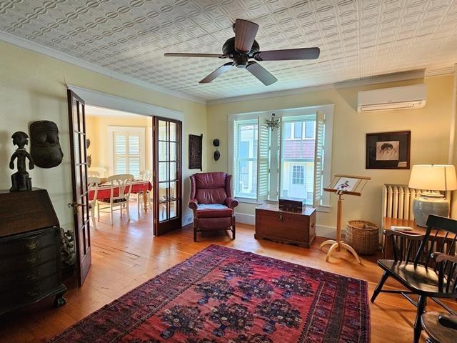 93 S Lincoln St, Keene, NH 03431 - living area with an AC wall unit, ornamental molding, an ornate ceiling, plenty of natural light, and wood finished floors
