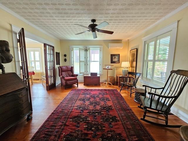 93 S Lincoln St, Keene, NH 03431 - sitting room with an AC wall unit, ornamental molding, wood finished floors, ceiling fan, and an ornate ceiling