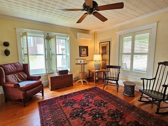 93 S Lincoln St, Keene, NH 03431 - sitting room with ornamental molding, wood finished floors, ceiling fan, an ornate ceiling, and a wall unit AC