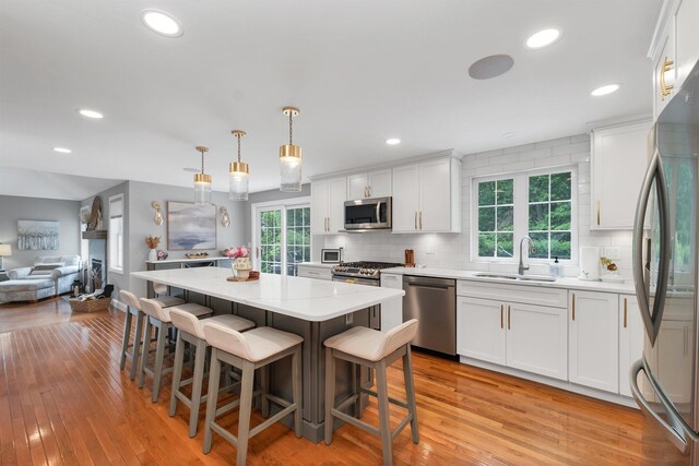 12 Julia Dr, Hooksett, NH 03106 - kitchen featuring stainless steel appliances, white cabinetry, decorative backsplash, light wood-style flooring, and a kitchen island
