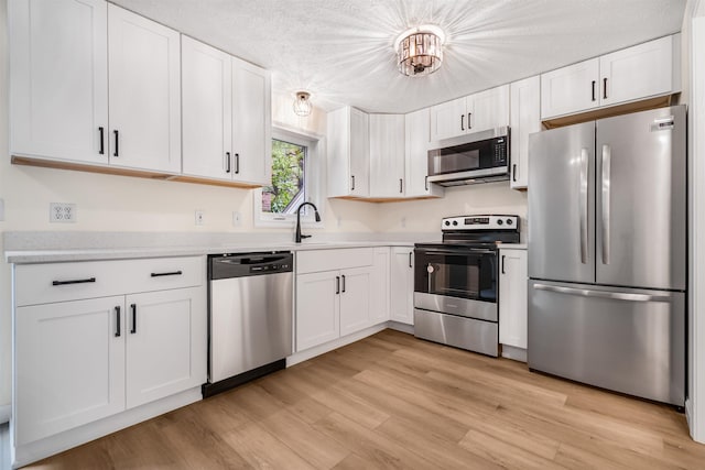 48 Eastmeadow Way, Manchester, NH 03109 - kitchen with stainless steel appliances, white cabinets, light wood-type flooring, and a textured ceiling