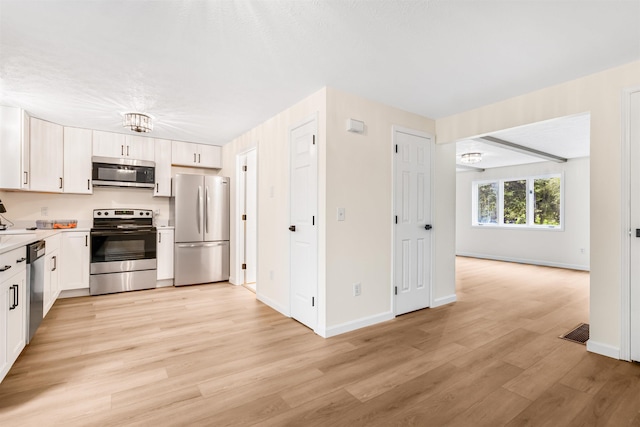 48 Eastmeadow Way, Manchester, NH 03109 - kitchen with appliances with stainless steel finishes, light countertops, light wood-style flooring, white cabinets, and open floor plan
