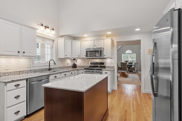 127 Hampton Mdws, Hampton, NH 03842 - kitchen featuring appliances with stainless steel finishes, white cabinetry, light wood-style flooring, tasteful backsplash, and recessed lighting