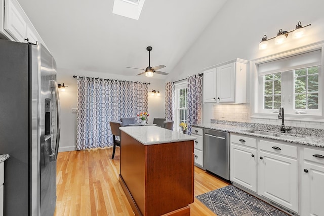 127 Hampton Mdws, Hampton, NH 03842 - kitchen with stainless steel appliances, white cabinetry, ceiling fan, tasteful backsplash, and a skylight