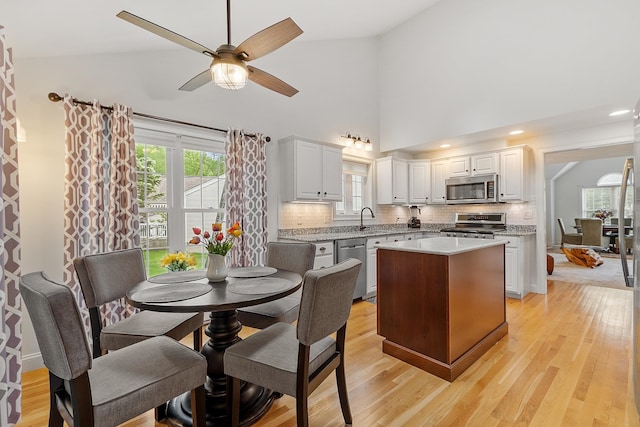 127 Hampton Mdws, Hampton, NH 03842 - kitchen featuring stainless steel appliances, decorative backsplash, a center island, ceiling fan, and high vaulted ceiling