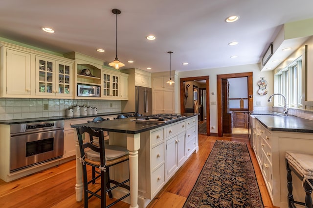 331 Rte 100 N, Plymouth, VT 05056 - kitchen with appliances with stainless steel finishes, dark countertops, a kitchen island, decorative backsplash, and a breakfast bar area