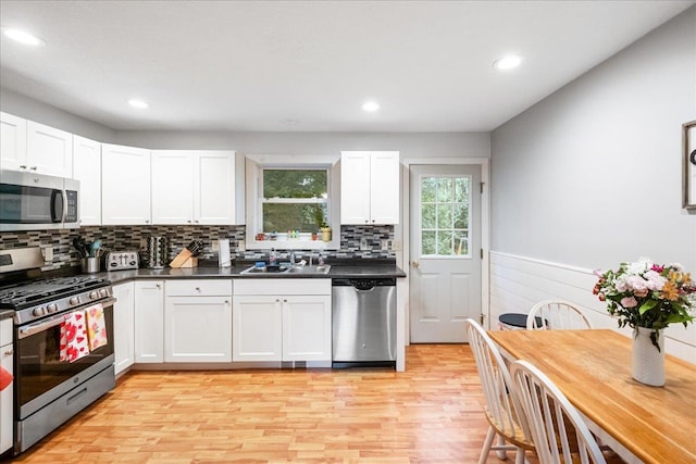 155 Woodcrest Cir, Milton, VT 05468 - kitchen with stainless steel appliances, light wood finished floors, white cabinets, a wainscoted wall, and dark countertops