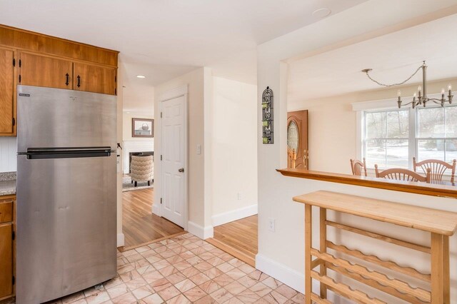 8 Woodridge Rd, Durham, NH 03824 - kitchen with freestanding refrigerator, a chandelier, brown cabinets, and recessed lighting