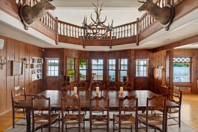 68 Sewall Rd, Wolfeboro, NH 03894 - dining space with wooden walls, light wood-style flooring, and a chandelier