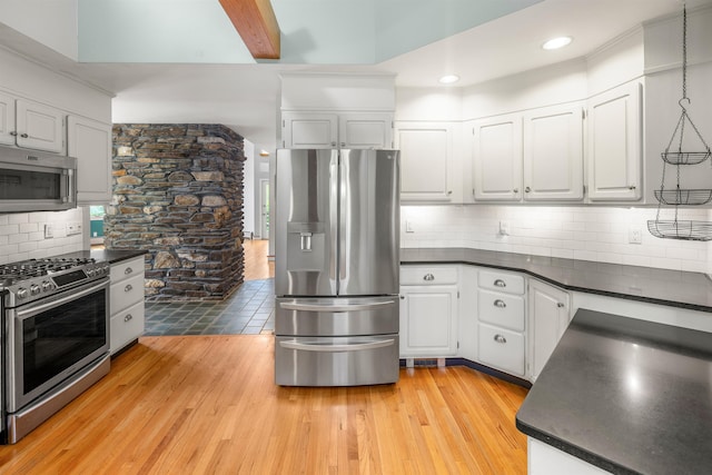 650 Perry Lea Rd, Waterbury, VT 05676 - kitchen with appliances with stainless steel finishes, dark countertops, light wood finished floors, decorative backsplash, and white cabinetry