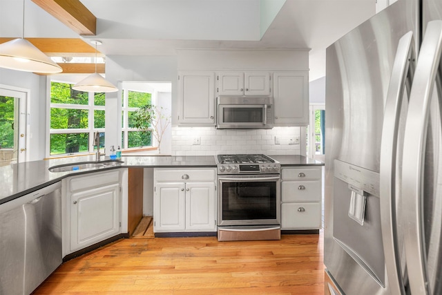 650 Perry Lea Rd, Waterbury, VT 05676 - kitchen with appliances with stainless steel finishes, dark countertops, light wood-style floors, tasteful backsplash, and white cabinets