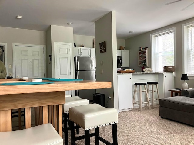 45 Kancamagus Hwy Unit 2, Woodstock, NH 03262 - kitchen with freestanding refrigerator, a kitchen breakfast bar, white cabinets, and light carpet
