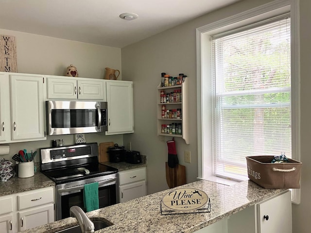 45 Kancamagus Hwy Unit 2, Woodstock, NH 03262 - kitchen with stainless steel appliances, white cabinets, plenty of natural light, and light stone countertops