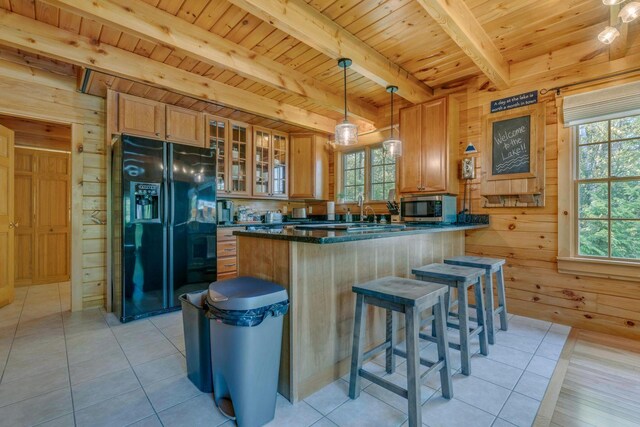 67 Cardinal Ln, Smithfield, ME 04978 - kitchen with black fridge, stainless steel microwave, a wooden ceiling with exposed beams, wood walls, and healthy amount of natural light