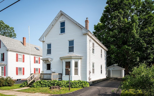 4 Walnut St, Exeter, NH 03833 - view of front facade featuring an outdoor structure, a garage, a chimney, and asphalt driveway