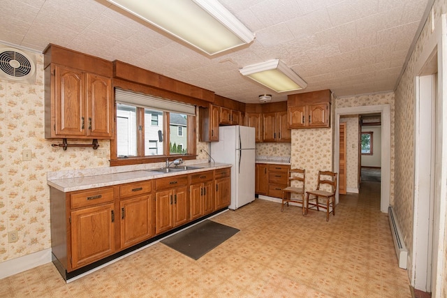 4 Walnut St, Exeter, NH 03833 - kitchen with freestanding refrigerator, light floors, brown cabinetry, baseboard heating, and wallpapered walls