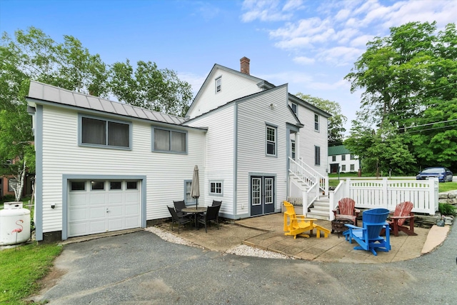 235 Dartmouth College Hwy, Haverhill, NH 03765 - back of house with driveway, a metal roof, a fire pit, an attached garage, and a chimney