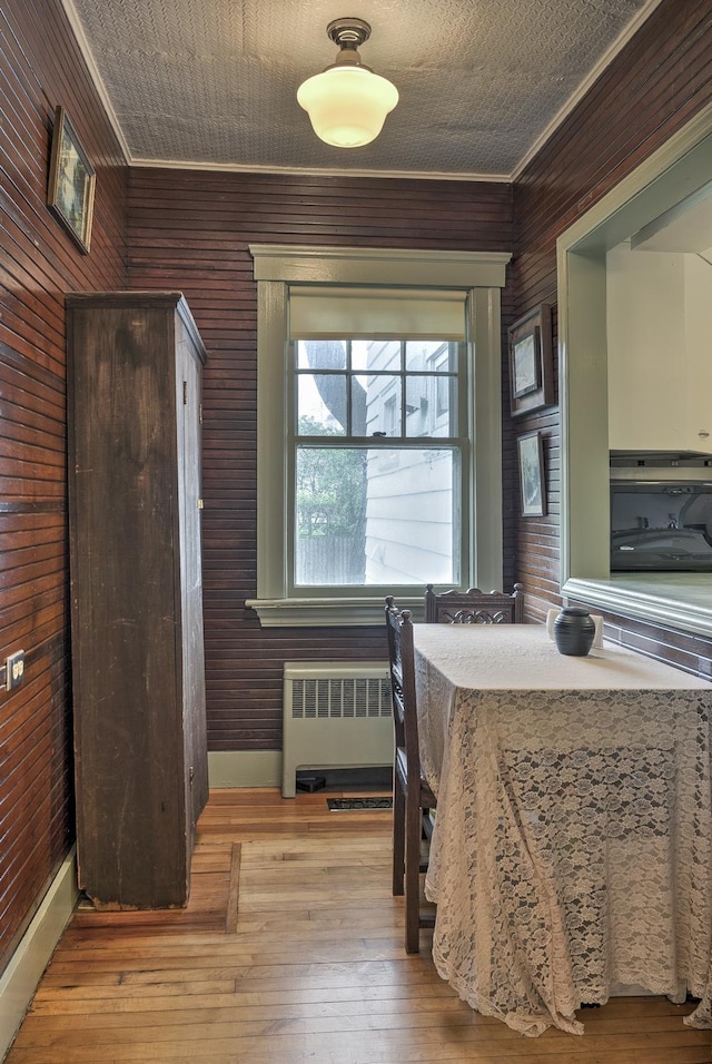 45 School St, Keene, NH 03431 - dining space featuring crown molding, wood walls, hardwood / wood-style floors, and radiator heating unit