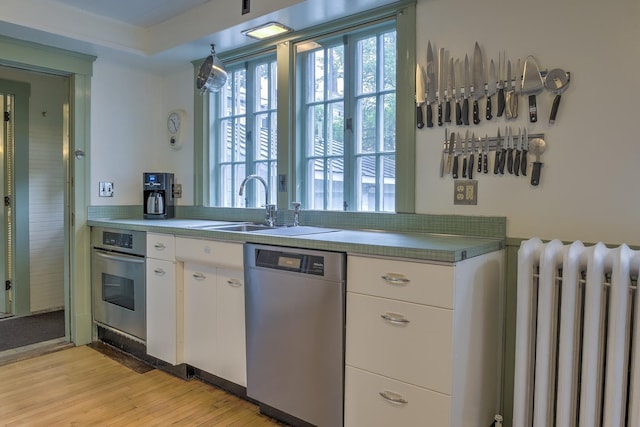 45 School St, Keene, NH 03431 - kitchen featuring stainless steel appliances, radiator heating unit, white cabinets, and light wood-type flooring