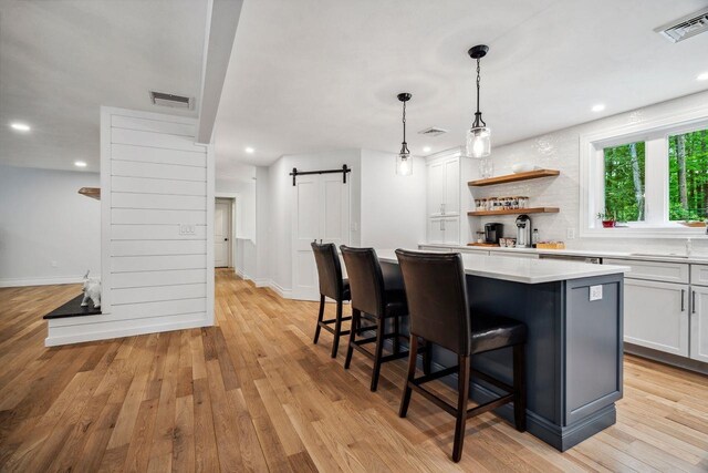 10 Lawrence Ln, Hollis, NH 03049 - kitchen with a barn door, light wood finished floors, a center island, a breakfast bar, and recessed lighting