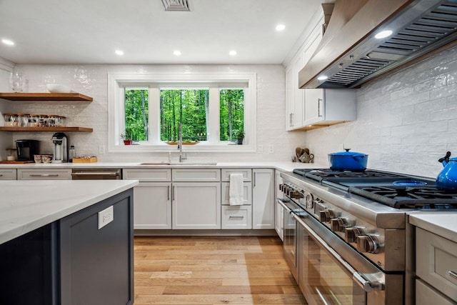 10 Lawrence Ln, Hollis, NH 03049 - kitchen featuring range with two ovens, premium range hood, light wood-style flooring, white cabinets, and backsplash
