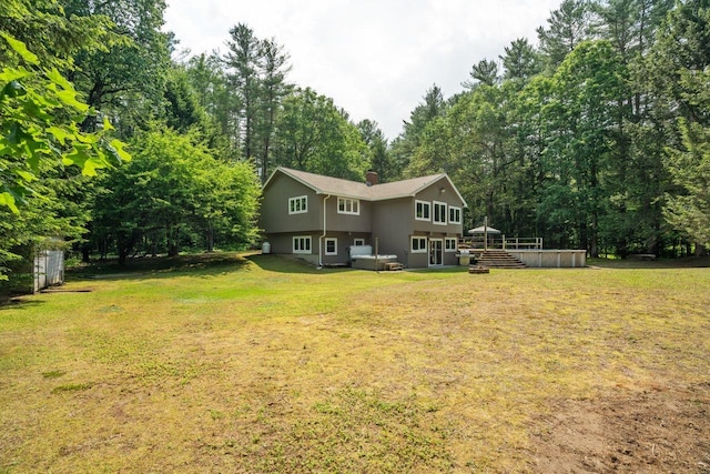 10 Lawrence Ln, Hollis, NH 03049 - rear view of property featuring a chimney, a yard, view of wooded area, and stucco siding