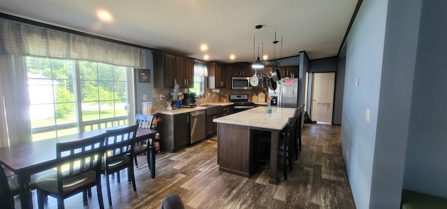 5 Mildred Ave, Raymond, NH 03077 - kitchen featuring appliances with stainless steel finishes, tasteful backsplash, dark brown cabinetry, dark wood finished floors, and hanging light fixtures