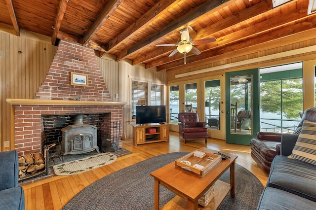 310 Bear Is, Meredith, NH 03253 - living room featuring a wood stove, a wooden ceiling with exposed beams, wood-type flooring, ceiling fan, and wood walls