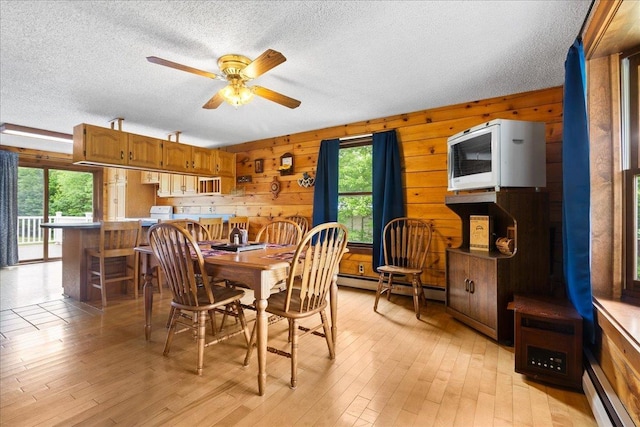 110 W Milan Rd, Milan, NH 03588 - dining room featuring plenty of natural light, a textured ceiling, a baseboard heating unit, light wood-style flooring, and wooden walls