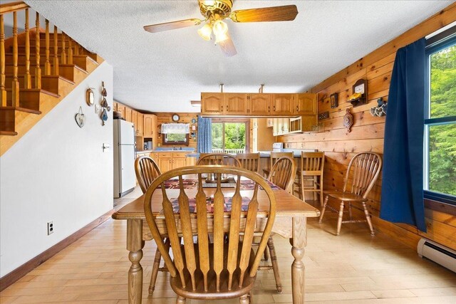 110 W Milan Rd, Milan, NH 03588 - dining room featuring a baseboard radiator, light wood-type flooring, a textured ceiling, ceiling fan, and stairs