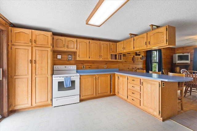 110 W Milan Rd, Milan, NH 03588 - kitchen with electric stove, a peninsula, a textured ceiling, a kitchen breakfast bar, and wood walls