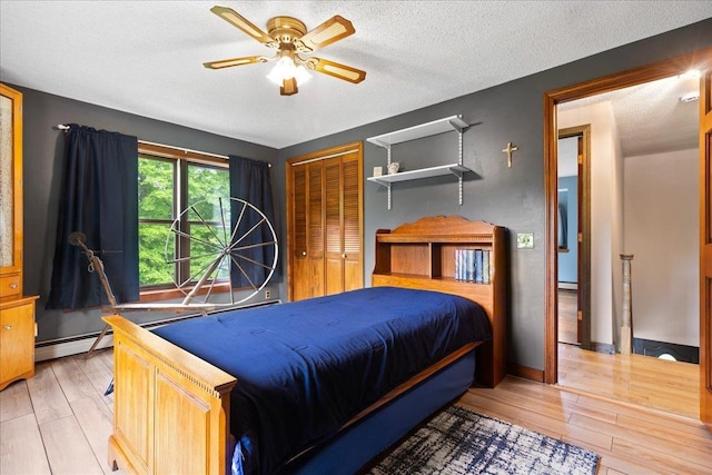 110 W Milan Rd, Milan, NH 03588 - bedroom featuring light wood-style floors, baseboard heating, a closet, a textured ceiling, and ceiling fan