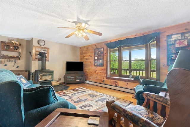110 W Milan Rd, Milan, NH 03588 - living room with a wood stove, a ceiling fan, wood finished floors, a textured ceiling, and baseboard heating