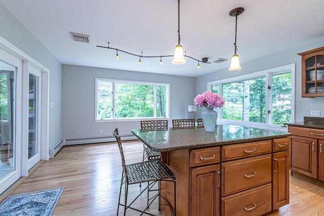 28 New Searles Rd, Nashua, NH 03062 - kitchen with light wood-style flooring, brown cabinetry, a baseboard heating unit, and a breakfast bar area