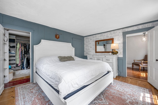 8 Main St, Brookline, NH 03033 - bedroom featuring light wood-style flooring, wallpapered walls, a closet, a walk in closet, and wainscoting