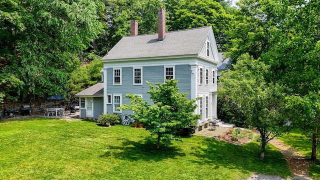 8 Main St, Brookline, NH 03033 - view of front facade with a shingled roof, a front yard, a chimney, and a patio