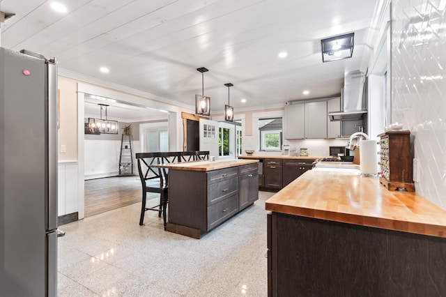6 Rainbow Dr, Ossipee, NH 03864 - kitchen featuring butcher block counters, freestanding refrigerator, a kitchen bar, wall chimney range hood, and crown molding