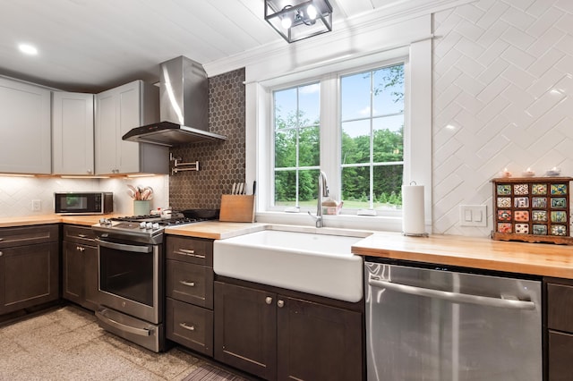 6 Rainbow Dr, Ossipee, NH 03864 - kitchen with stainless steel appliances, wall chimney range hood, wooden counters, crown molding, and dark brown cabinetry