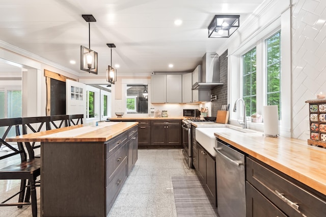 6 Rainbow Dr, Ossipee, NH 03864 - kitchen with butcher block countertops, stainless steel appliances, wall chimney exhaust hood, a kitchen breakfast bar, and dark brown cabinetry