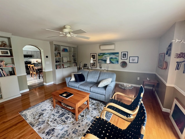 653 Skyboro E Rd, Pownal, VT 05261 - living room featuring a wall unit AC, arched walkways, wood finished floors, and a ceiling fan