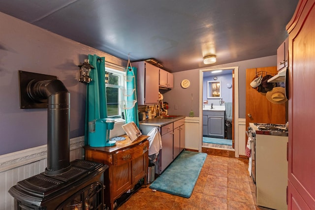 3123 Carter Hill Rd, Highgate, VT 05488 - kitchen featuring gas stove, under cabinet range hood, wainscoting, and a wood stove