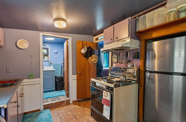3123 Carter Hill Rd, Highgate, VT 05488 - kitchen with freestanding refrigerator, gas range, under cabinet range hood, and wainscoting