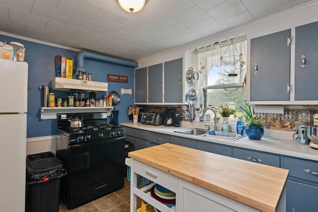 3123 Carter Hill Rd, Highgate, VT 05488 - kitchen with black gas range oven, freestanding refrigerator, under cabinet range hood, wood counters, and crown molding