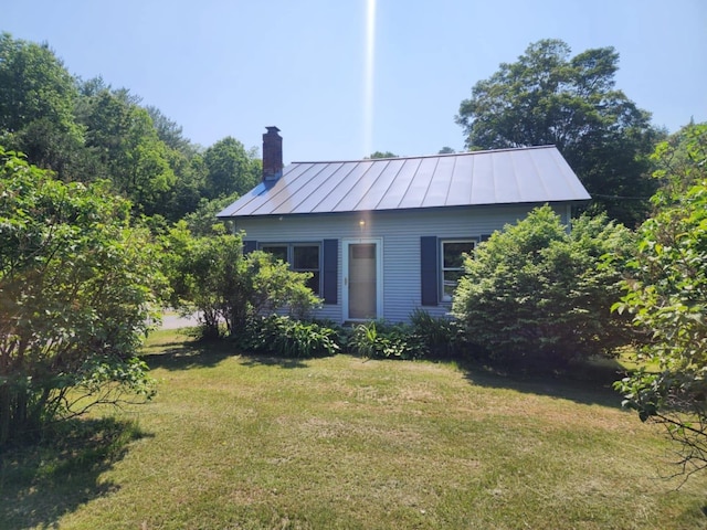1082 W River Rd, Brattleboro, VT 05301 - view of front facade featuring a standing seam roof, a chimney, a front lawn, and a metal roof