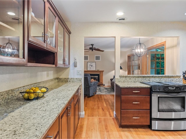 66 Dunder Rd, Burlington, VT 05401 - kitchen featuring electric range, light wood-style flooring, a lit fireplace, and light stone countertops