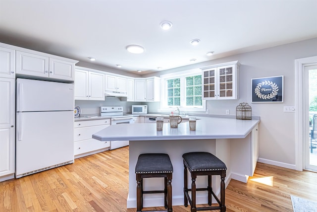 48 Cider Mill Rd, Bedford, NH 03110 - kitchen with white appliances, a breakfast bar, under cabinet range hood, a peninsula, and light wood-style floors