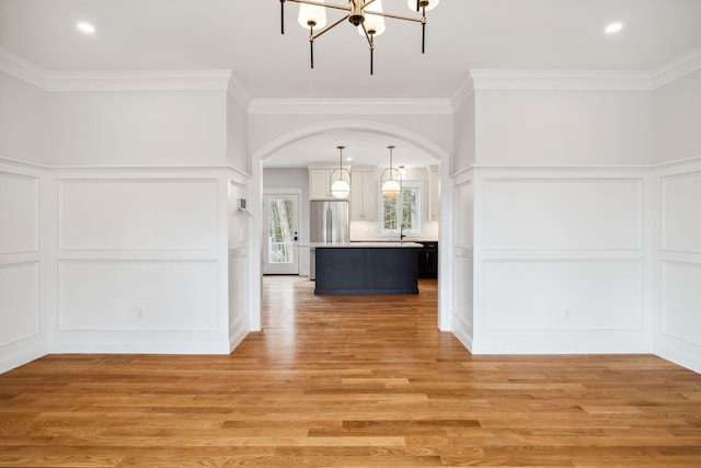 131 Exeter Rd, North Hampton, NH 03862 - kitchen featuring a decorative wall, a chandelier, arched walkways, a kitchen island, and ornamental molding