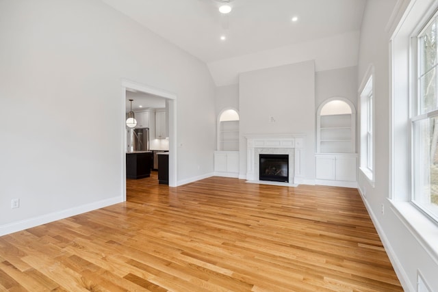 131 Exeter Rd, North Hampton, NH 03862 - unfurnished living room featuring high vaulted ceiling, built in shelves, light wood finished floors, a premium fireplace, and recessed lighting