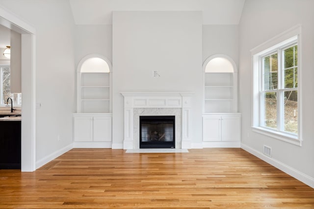 131 Exeter Rd, North Hampton, NH 03862 - unfurnished living room featuring built in features, healthy amount of natural light, light wood-style floors, a towering ceiling, and a fireplace