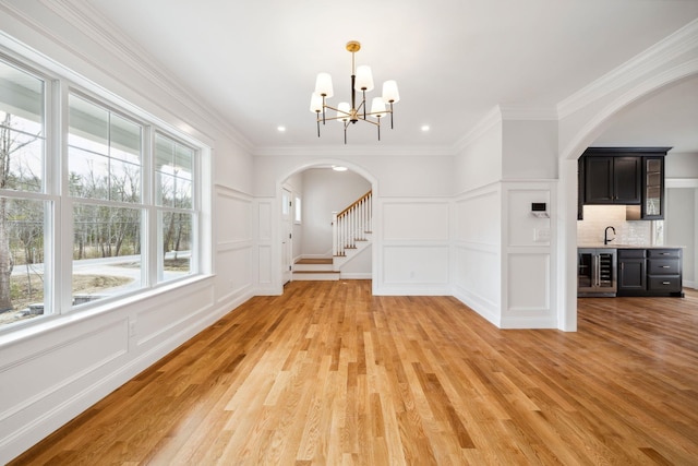 131 Exeter Rd, North Hampton, NH 03862 - unfurnished dining area with a decorative wall, arched walkways, beverage cooler, light wood-type flooring, and a chandelier